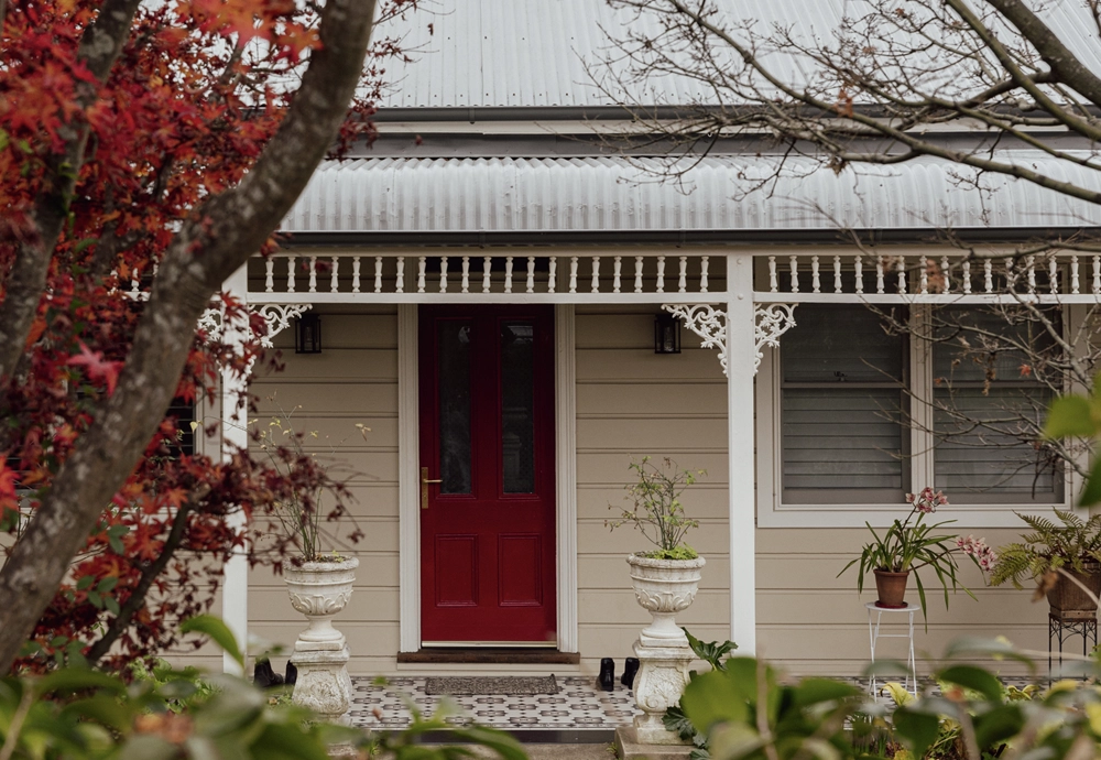 Front shot of a house with red tree beside it